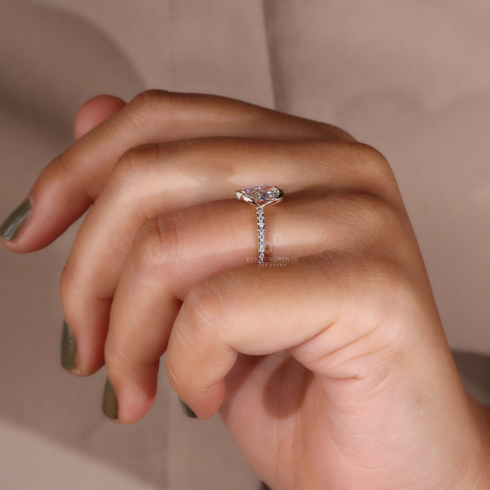 A model showcasing a pear shaped engagement ring with a half bezel setting, highlighting the brilliance of the pear cut diamond.