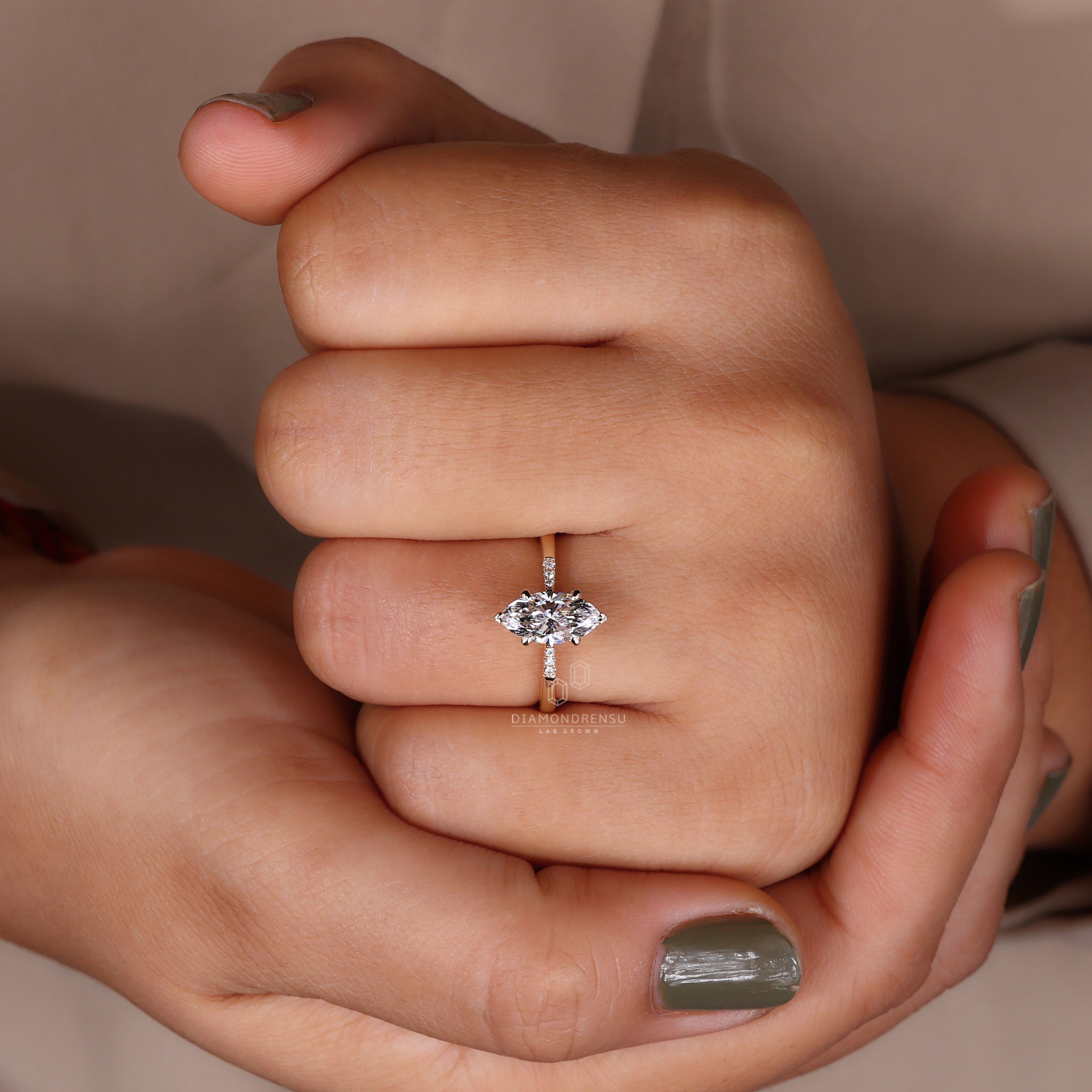 Model wearing a yellow gold engagement ring with a marquise diamond and round side stones.