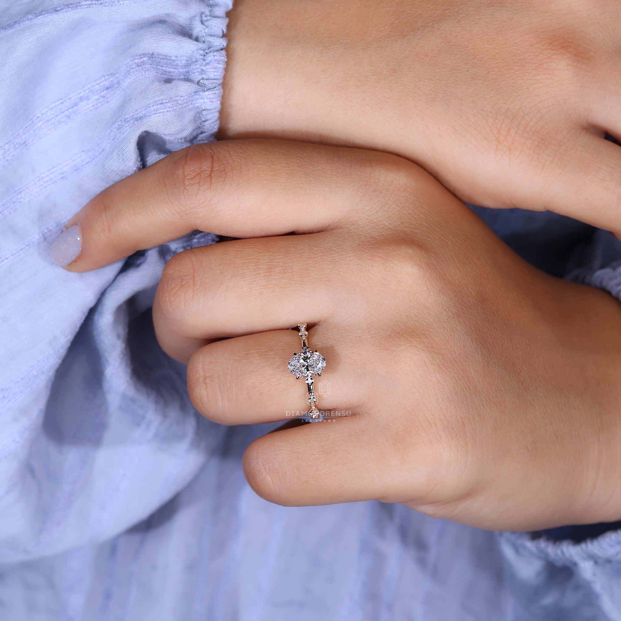 Close-up of a hidden halo oval engagement ring on a woman's hand, featuring a yellow gold band.