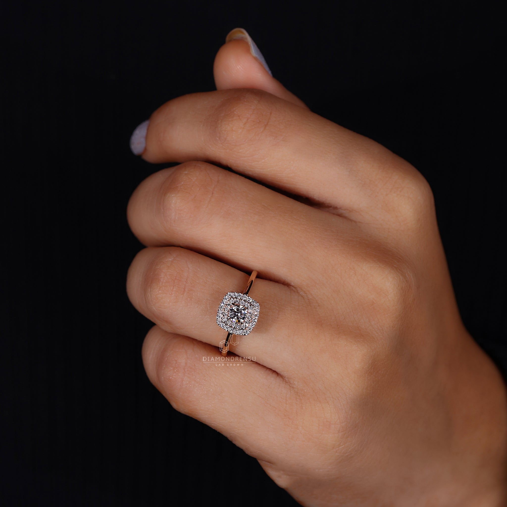 A woman's hand gracefully displaying a double halo engagement ring with a central round diamond, accentuated by a dual halo of diamonds, on a polished gold band.