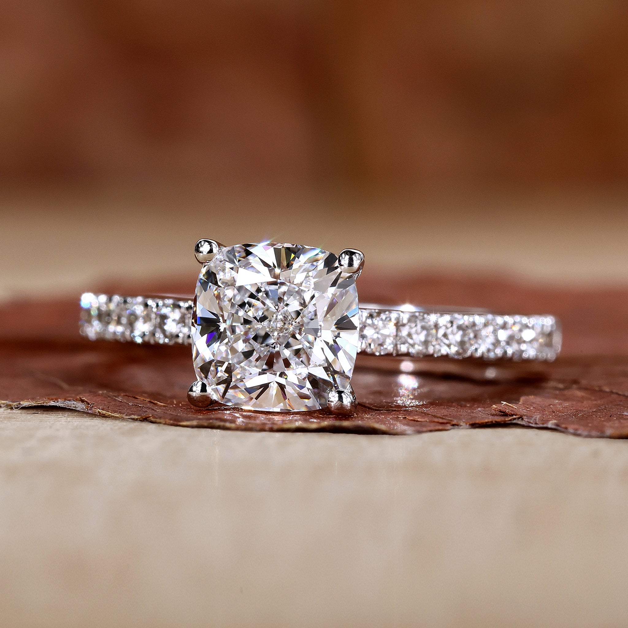 Cushion cut engagement ring with round prong and pave diamond accents.