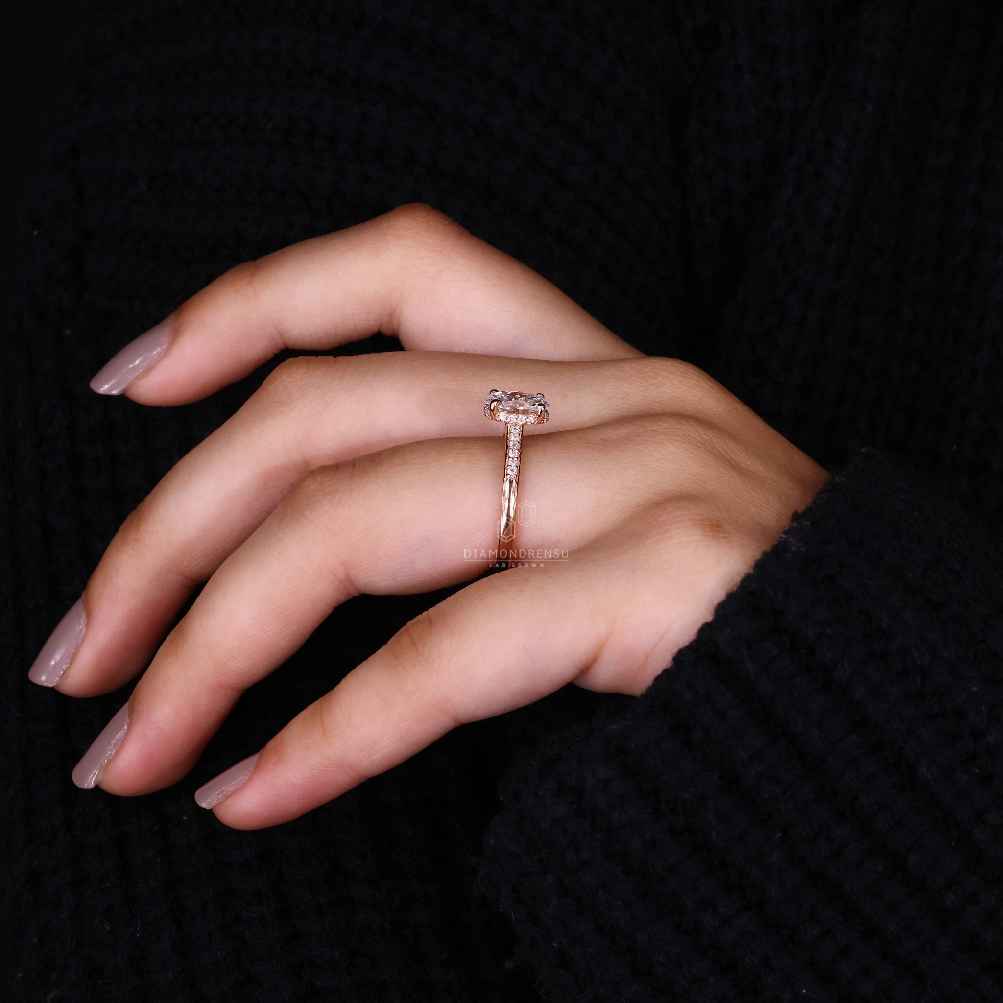 Model's hand adorned with an oval lab grown diamond engagement ring, emphasizing the open gallery setting and sparkling design.