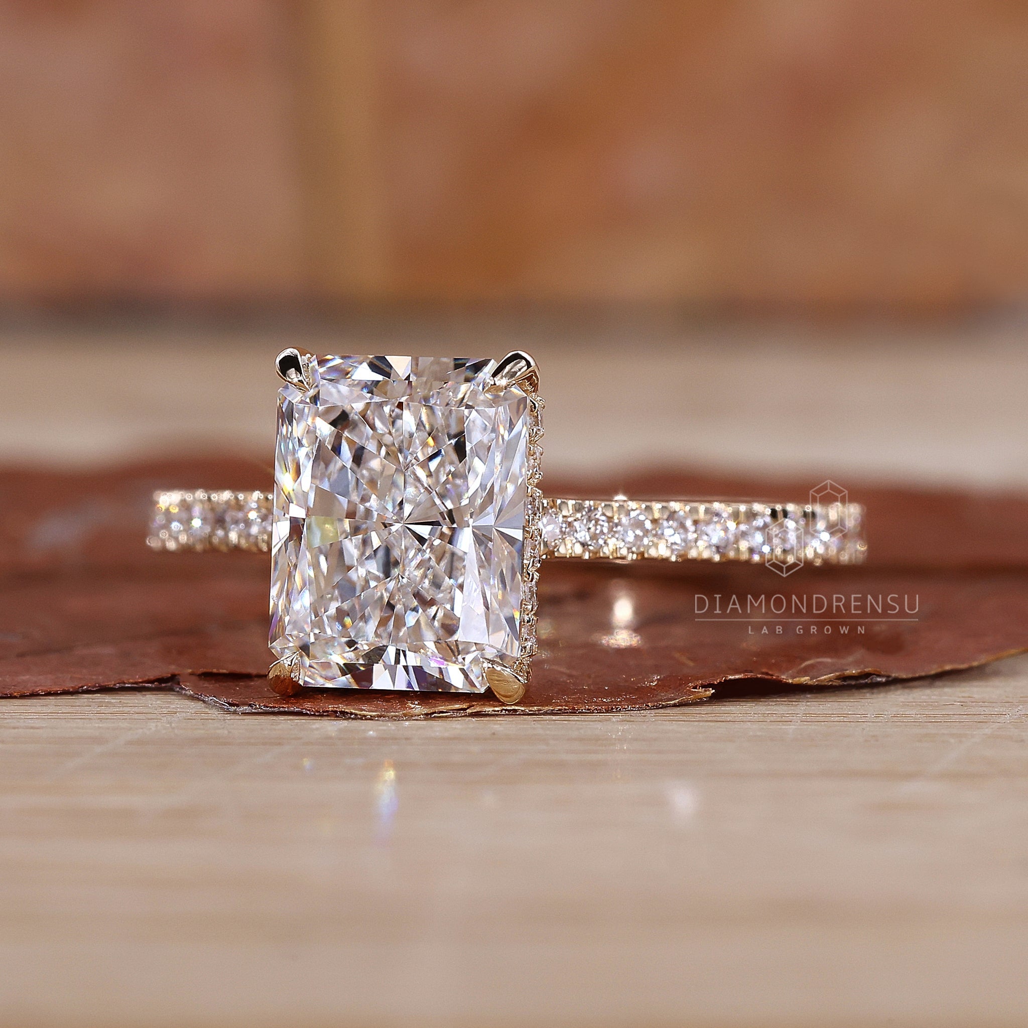 Radiant cut engagement ring with pave diamonds and hidden halo, displayed in an elegant ring box