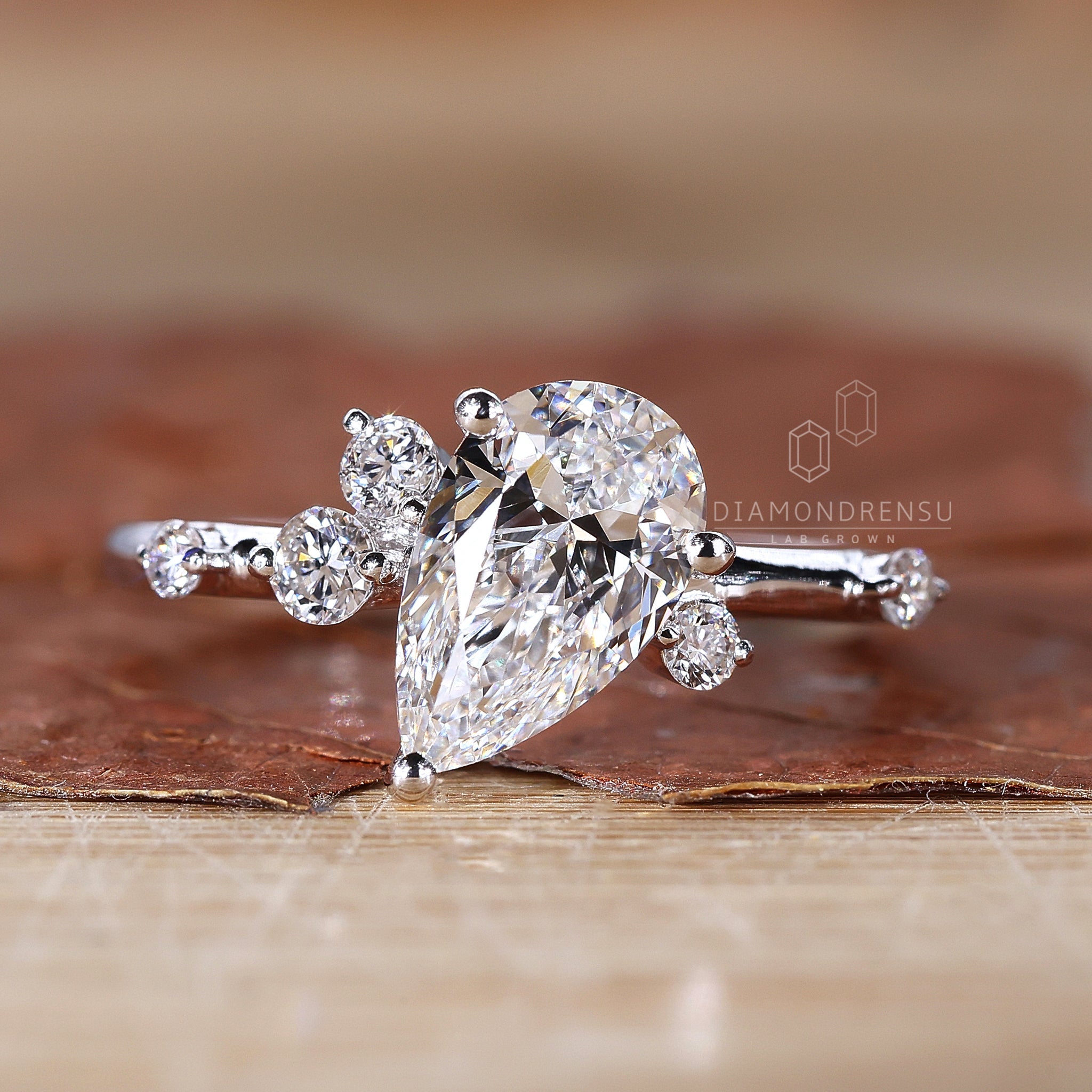 White gold pear cut diamond engagement ring with round side stones and basket setting