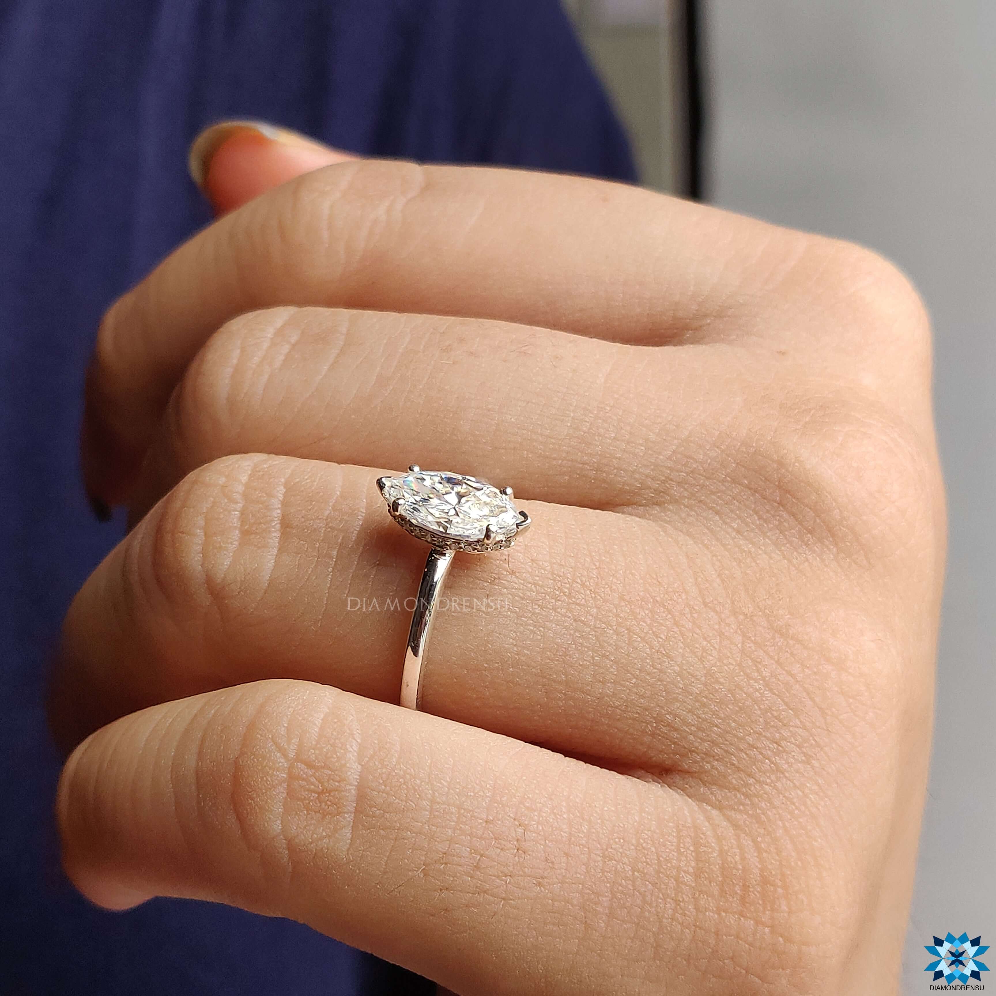 Charming moissanite engagement ring featuring a marquise cut and a beautiful 4 prong round engagement ring setting.